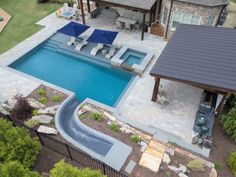 an aerial view of a backyard with a pool, patio and hot tub in the middle