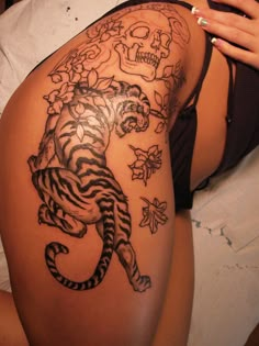 a woman's thigh with a tiger tattoo on it and flowers around her waist