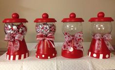 three red candy dispensers with bows and hearts on them sitting on a table