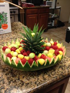 a pineapple and raspberry fruit arrangement on a kitchen counter