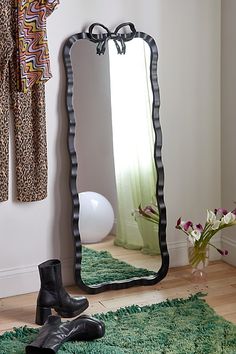 a pair of black boots sitting on top of a rug next to a large mirror