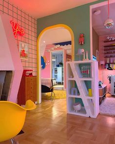 the interior of a child's bedroom with pink and green walls, white shelves, and yellow chairs