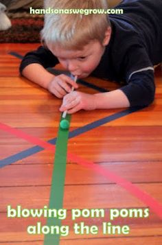 a little boy laying on the floor playing with tape