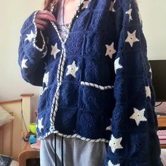 a woman wearing a blue sweater with white stars on it and holding a cell phone up to her ear