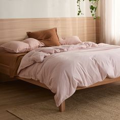 an unmade bed with pink sheets and pillows