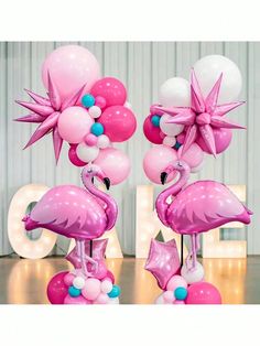 two flamingos are standing on top of balloons