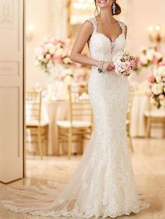 a woman in a wedding dress holding a bouquet and smiling at the camera while standing next to a table