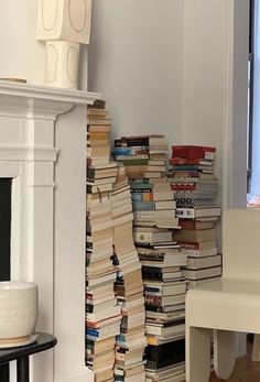 a stack of books sitting on top of a wooden floor next to a fire place