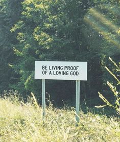 a sign that says be living proof of a loving god in front of some trees