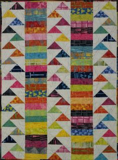 a multicolored quilt with many different shapes and sizes on the front, including triangles