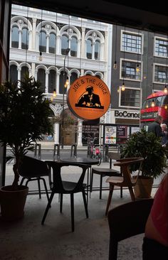 a restaurant with tables and chairs in front of a large window that has an orange sign on it