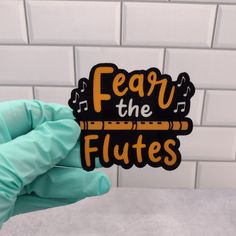 someone wearing gloves holding up a sticker that says fear the flutes