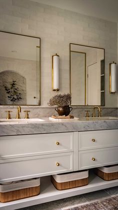 a bathroom with two sinks and three mirrors on the wall above them, along with gold accents