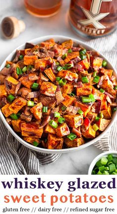 a bowl filled with sweet potato salad next to a bottle of whiskey