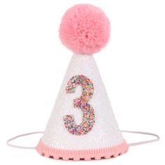 a pink and white party hat with the number 3 on it's side, decorated with multicolored sprinkles