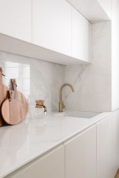 a kitchen with marble counter tops and white cabinets, along with wooden cutting boards on the backsplash