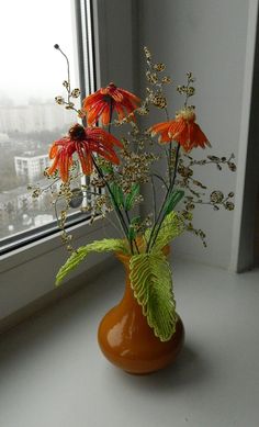 an orange vase filled with flowers on top of a window sill