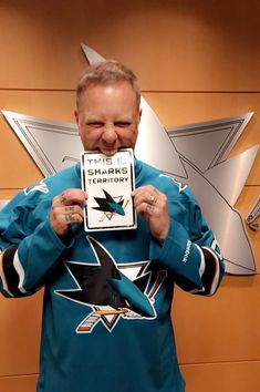 a man holding up a plaque in front of his face with the sharks logo on it