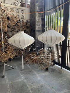 two white umbrellas sitting next to each other on top of a metal stand in front of a gate