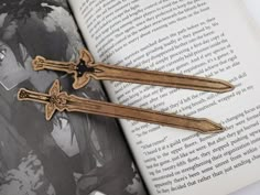 two wooden swords sitting on top of an open book