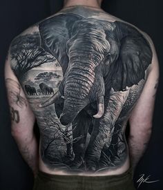 an elephant tattoo on the back of a man's left shoulder and upper arm