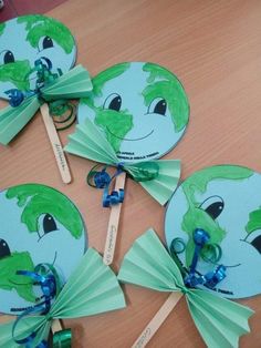 four green paper fans with blue bows on them sitting on a table next to two wooden spoons