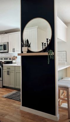 a black and white kitchen with a round mirror on the wall above the stove top