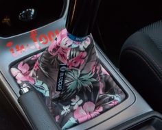 the interior of a car with a flowery seat cover on it and a bottle in the center console