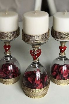 three clear glass vases with red roses in them and two white candles on top