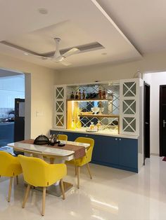 a dining room with yellow chairs and a white counter top in front of a window