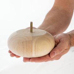 a person holding a wooden object with a screw in it