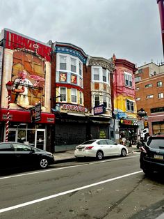 cars are parked on the street in front of some stores and buildings with advertisements painted on them