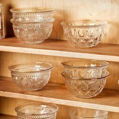 glass bowls are lined up on wooden shelves