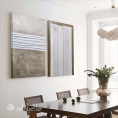 a dining room table with chairs and two paintings on the wall