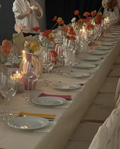 a long table is set up with plates and glasses for dinner guests to enjoy the meal