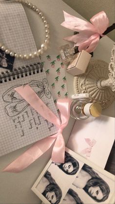 an open notebook with pink ribbon on top of it next to pictures and other items