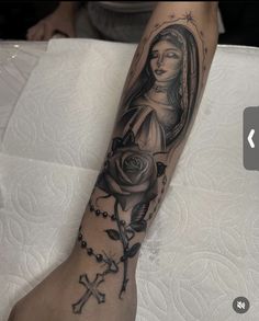 a woman with a rosary and rose tattoo on her leg