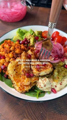 a white plate topped with chicken, beans and veggies next to a fork