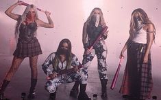 three women with long hair and makeup are standing in front of a wall holding guitars