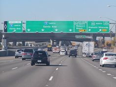 cars are driving down the highway with signs above them that point in different directions and direction