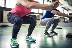 two people doing squats in a gym with one holding a kettle and the other standing up