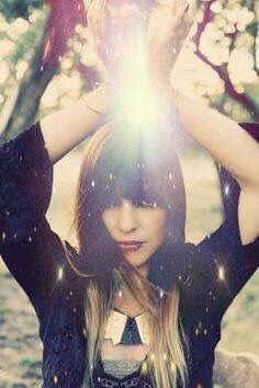 a woman holding her hands up in the air with sunlight shining through her hair and eyes