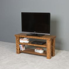 a flat screen tv sitting on top of a wooden stand in front of a gray wall