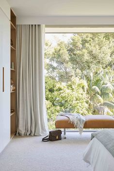 a bedroom with a large window and a bench in front of the window that is open