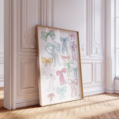 an empty frame with bows on it in front of a white wall and wooden floor