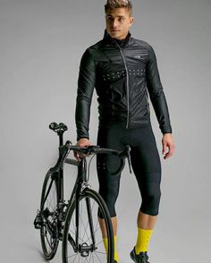 a man standing next to a bike in front of a gray background with yellow socks