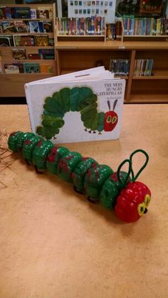 the very hungry caterpillar is sitting on the table in front of bookshelves