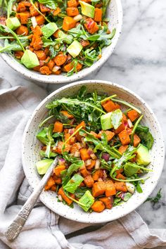 two bowls filled with salad on top of a table