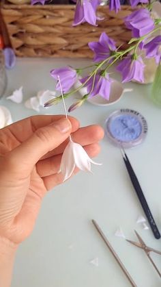 a person holding a flower in front of some scissors and other crafting supplies on a table