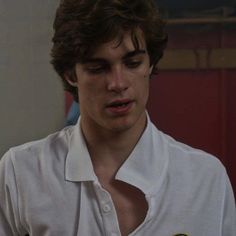 a young man wearing a white shirt looking at his cell phone